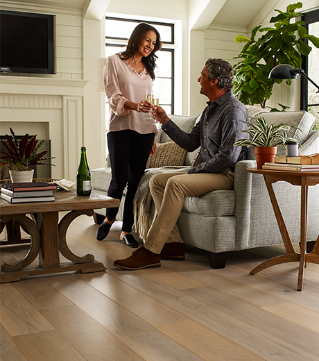 a couple drinking wine in a living room with wood-look luxury vinyl flooring from A Touch Of Magic Flooring in Emerald Isle, NC