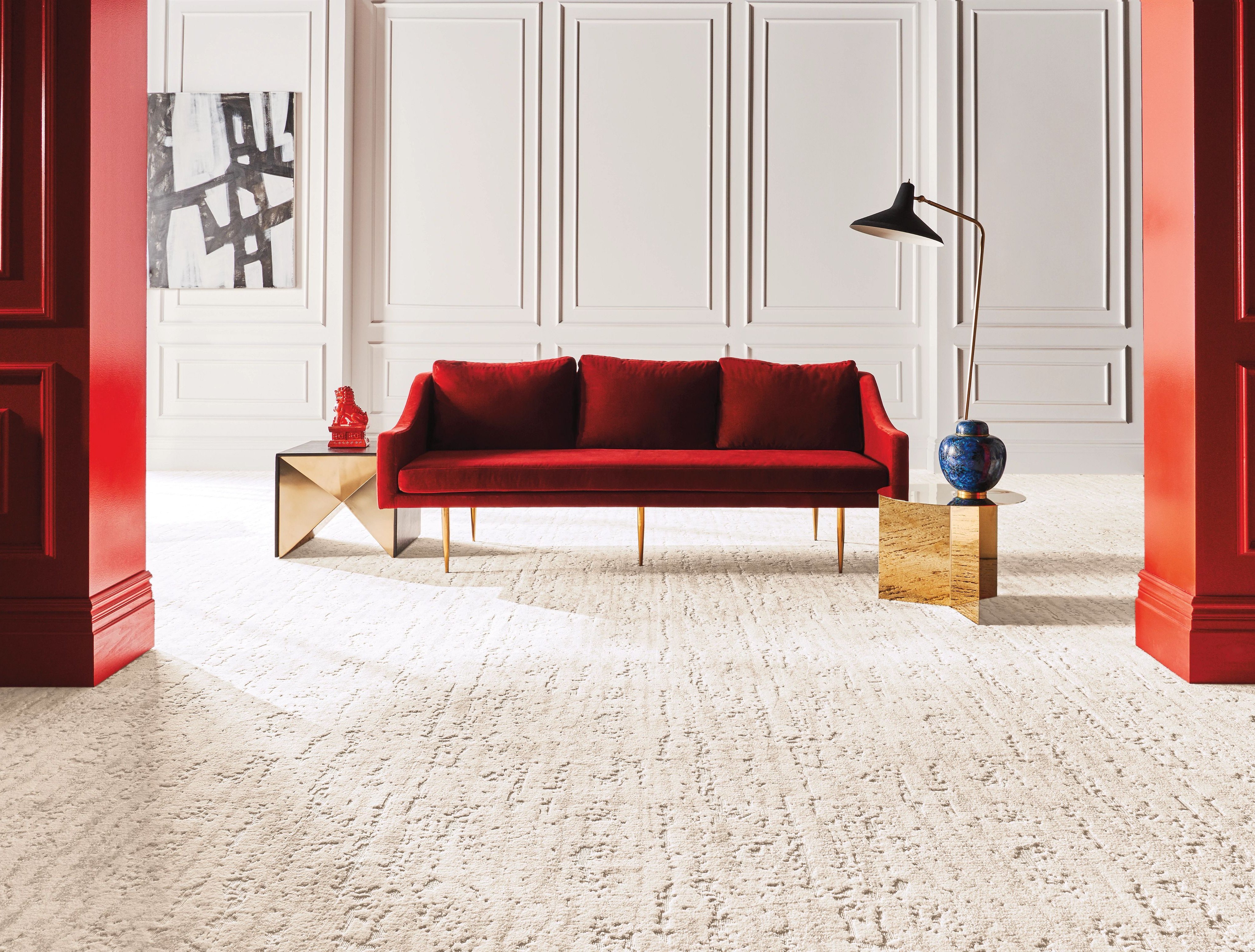 Bright living room with a red velvet couch and beige textured carpet from A Touch Of Magic Flooring in Emerald Isle, NC